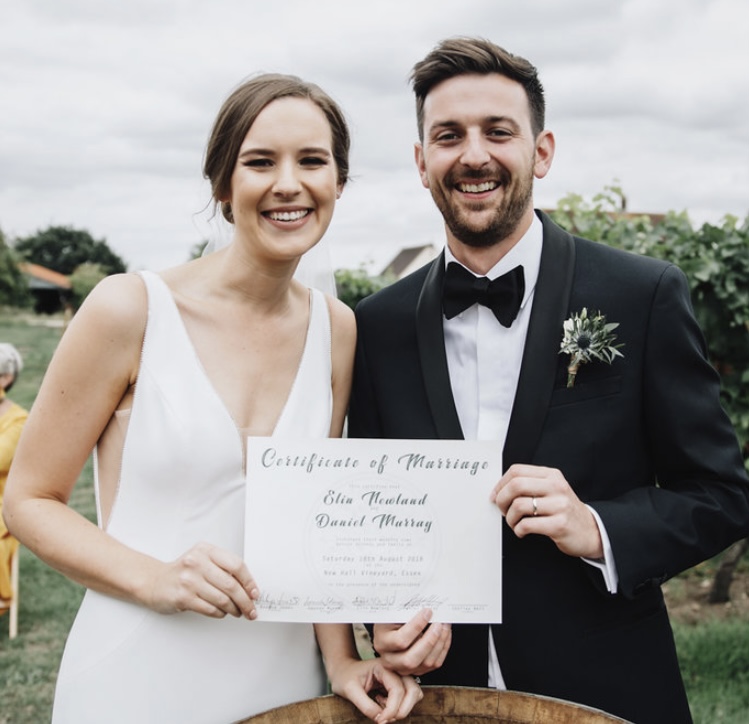 The bride and groom hold aloft their certificate of marriage in celebration of their professional, fun packed, personality filled, bespoke ceremony in an English vineyard, lead by Shelley Bell Celebrant