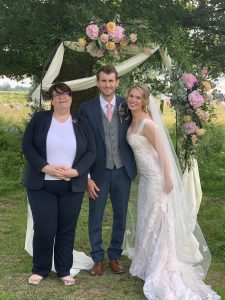 Celebrant poses with happy couple after outdoor ceremony