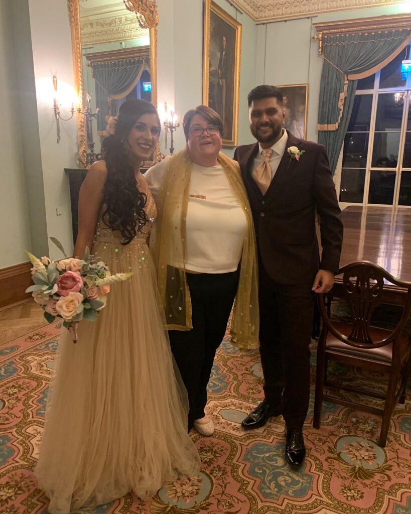 Bride and Groom pose with celebrant post ceremony in the blue room at Hylands House, Essex