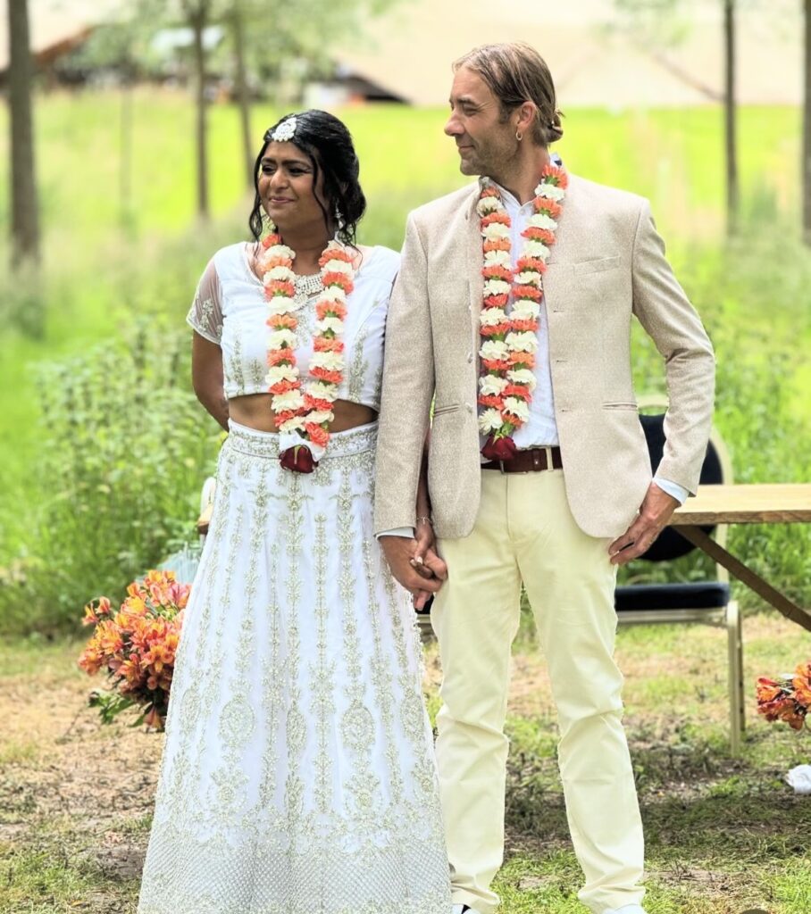 an asian bride and her new English husband, stand before their witnesses in a field ready to pledge their vows to each other.