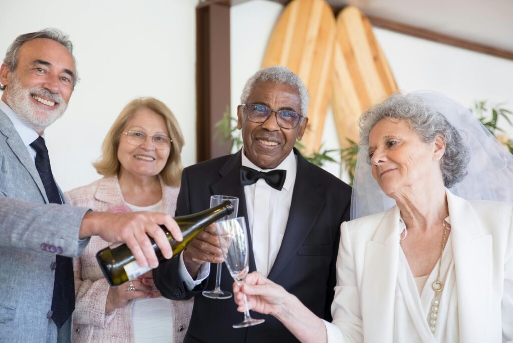 A bride dressed in white and a groom dressed in a black dinner jacket are having their drinks poured by their wedding guests as the fabulous speeches are being made at the wedding.