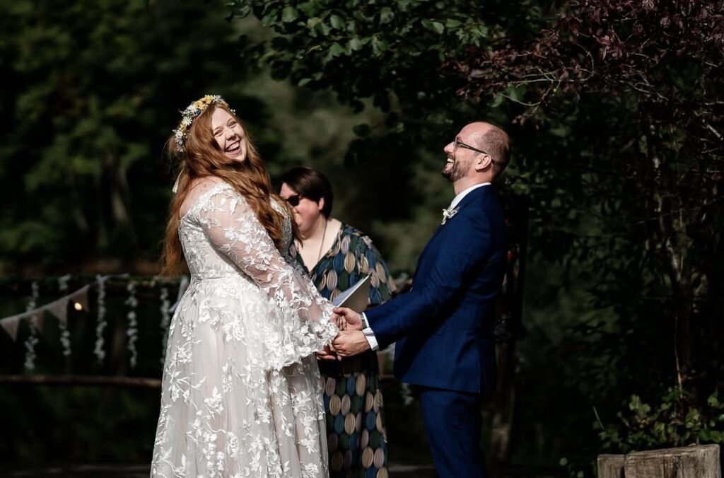 A bride and groom hold hands and laugh out loud at their Celebrant Led ceremony