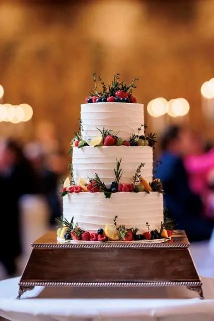 A Vegan wedding cake decorated with flowers and fruits across 3 tiers