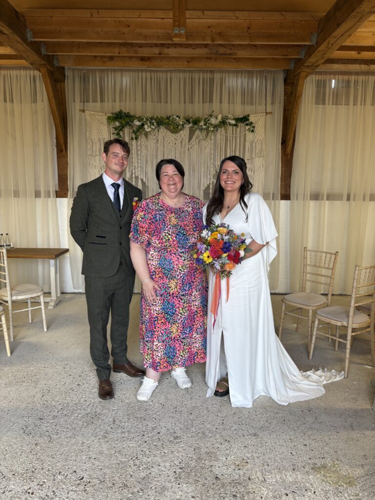 Shelley Bell celebrant stands in the middle of a bride and groom after they have just been married in front of their friends and family