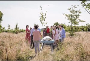 A group of people in bright clothes prepare to inter a body at a natural burial ground