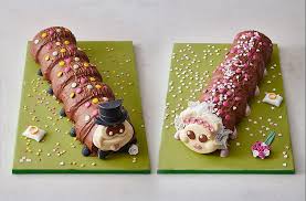 2 caterpillar cakes, one in a top hat to represent a groom and one in a veil to represent a bride.