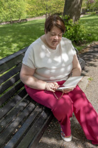 Shelley Bell sitting on a park bench with a notebook in hand