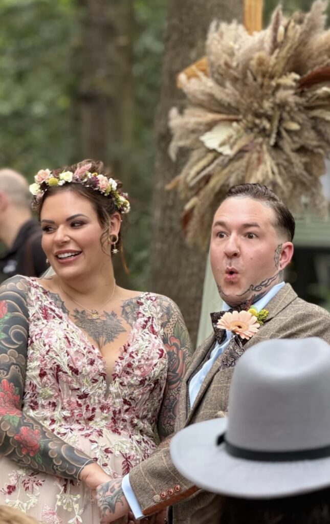 The bride smiles towards the guests as the groom pouts 