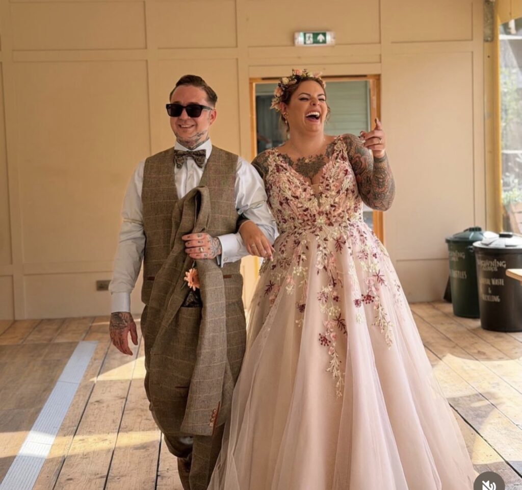 The groom wearing sunglasses enters the reception hall, hand in hand with his laughing bride.