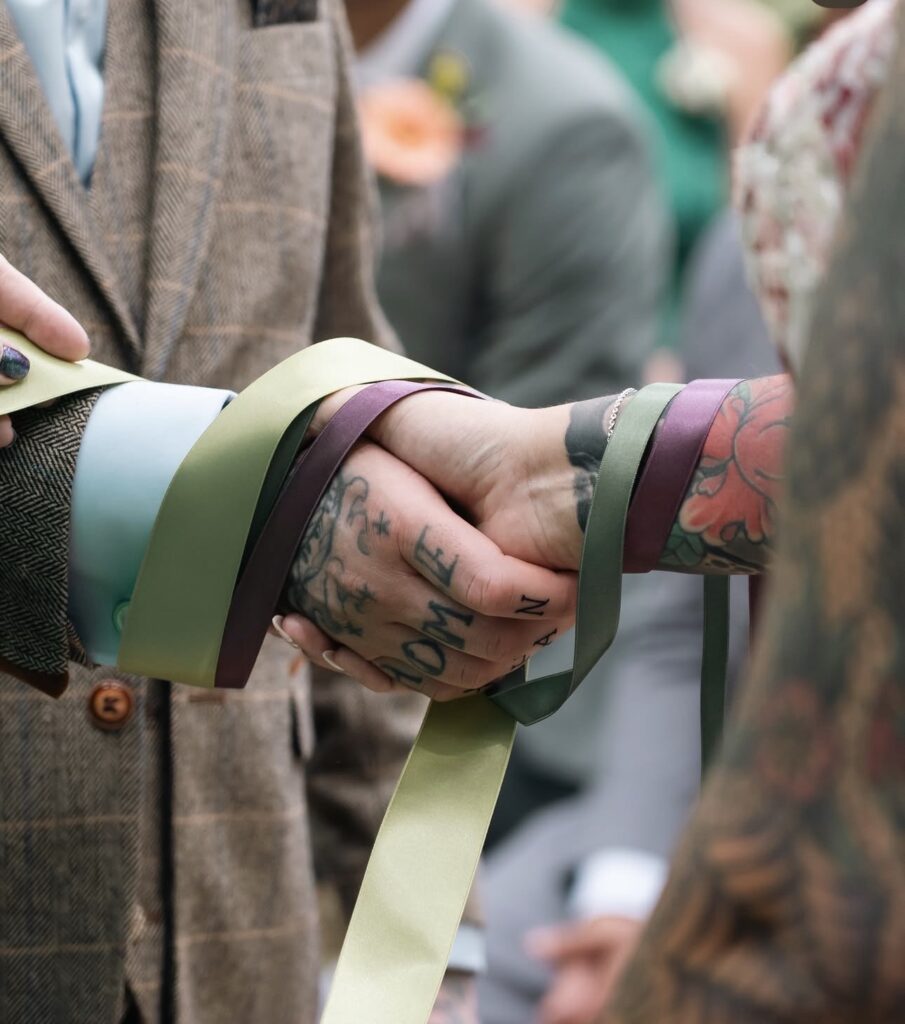 the bride and grooms hands are tied with ribbons