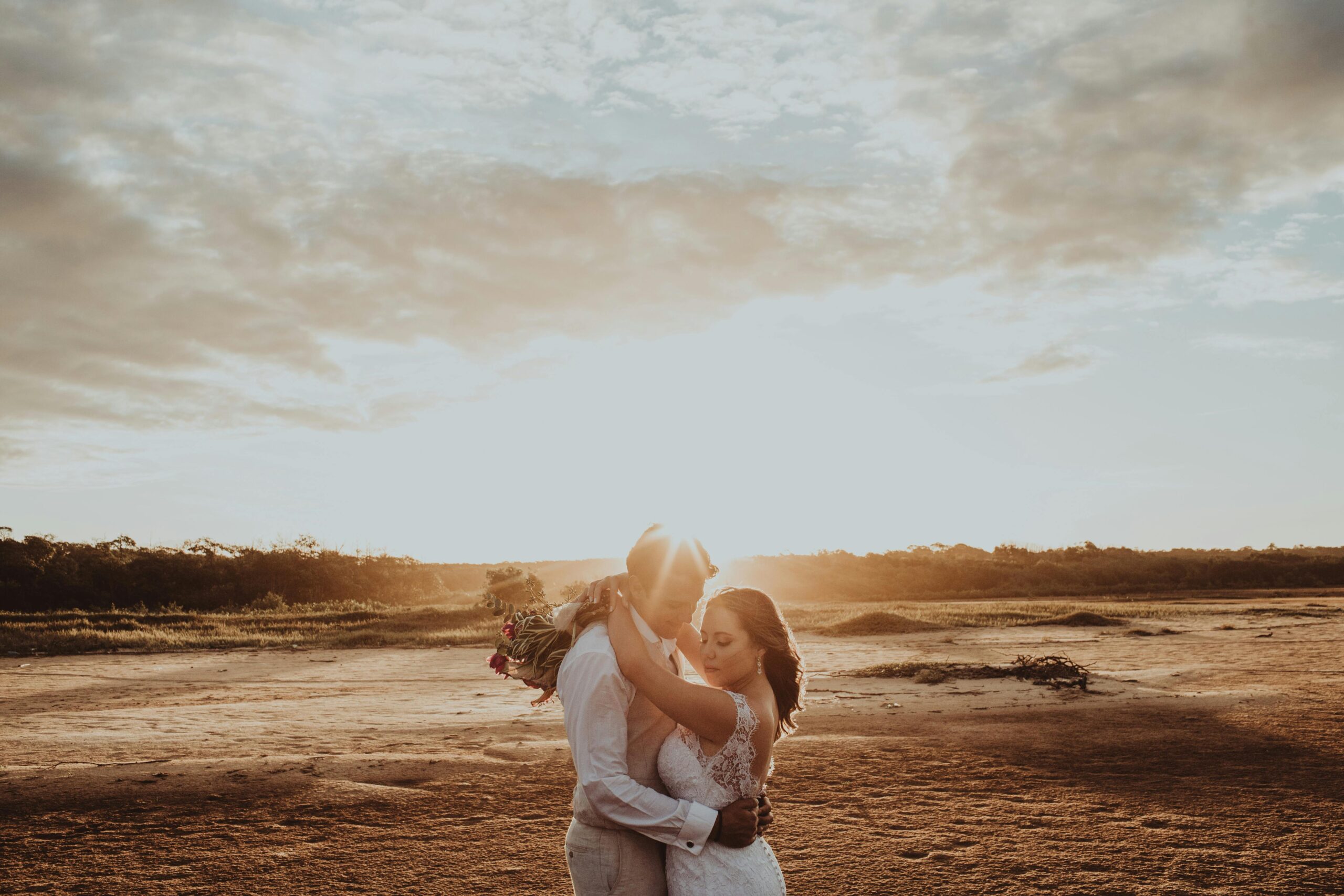 A couple stand in a desert backdrop at sunset having just completed their vow renewal ceremony.