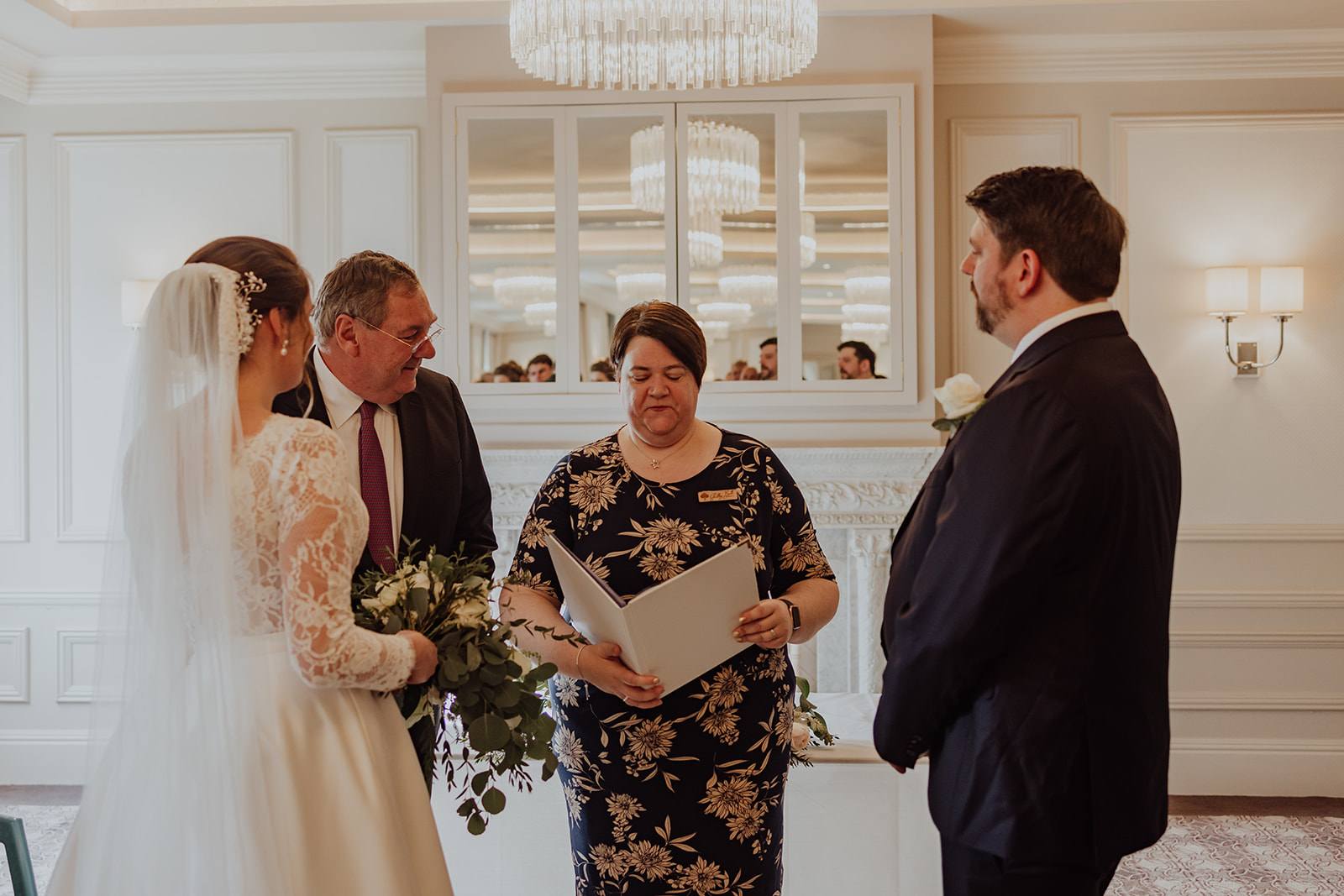 A bride in a white dress is escorted to the ceremony area by her father, attended by Shelley Bell Celebrant and her soon to be husband.