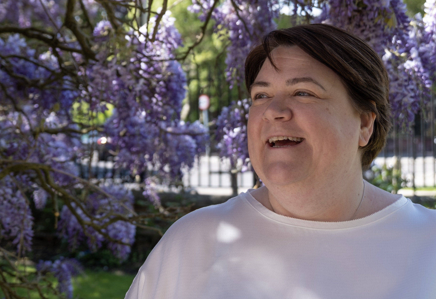 Shelley Bell Smiling in front of some Wisteria